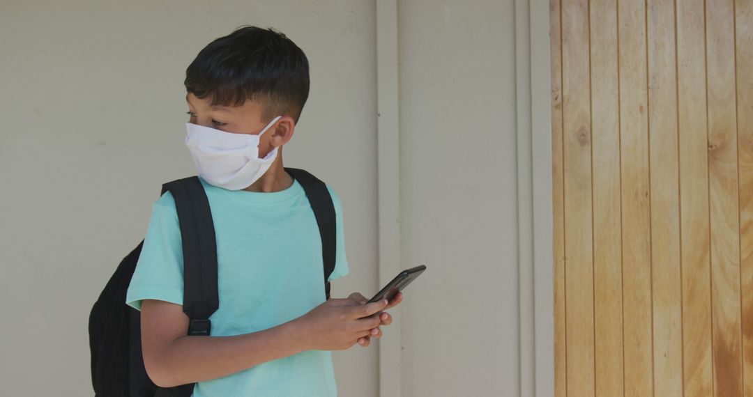 Child Wearing Face Mask Using Smartphone During School Day