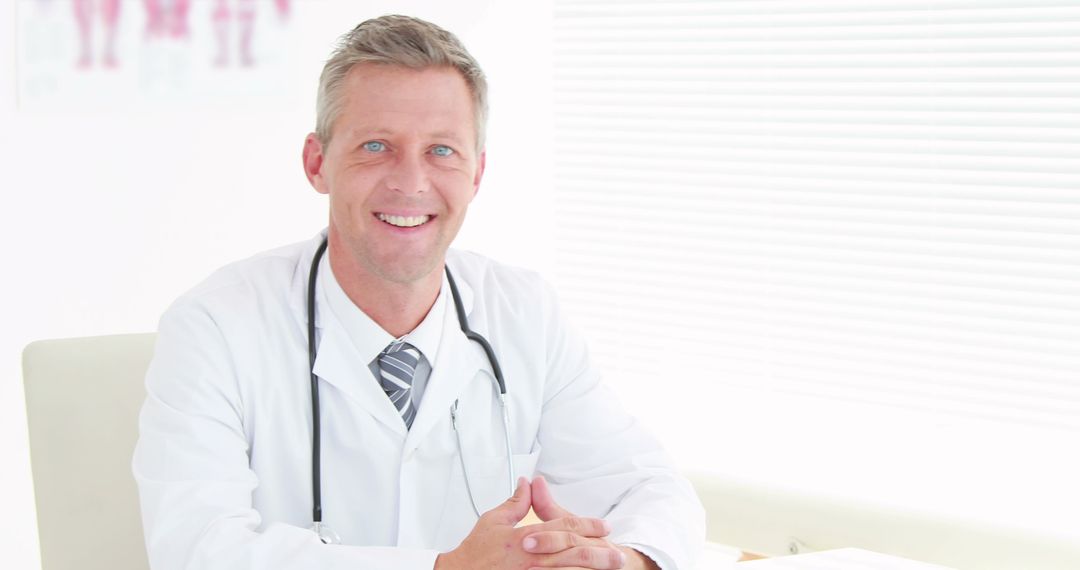 Smiling Male Doctor Sitting in Medical Office - Free Images, Stock Photos and Pictures on Pikwizard.com