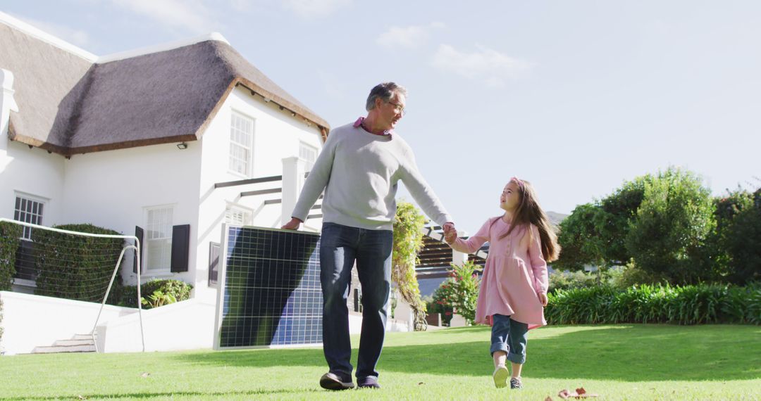 Grandfather and granddaughter carrying solar panel in garden - Free Images, Stock Photos and Pictures on Pikwizard.com