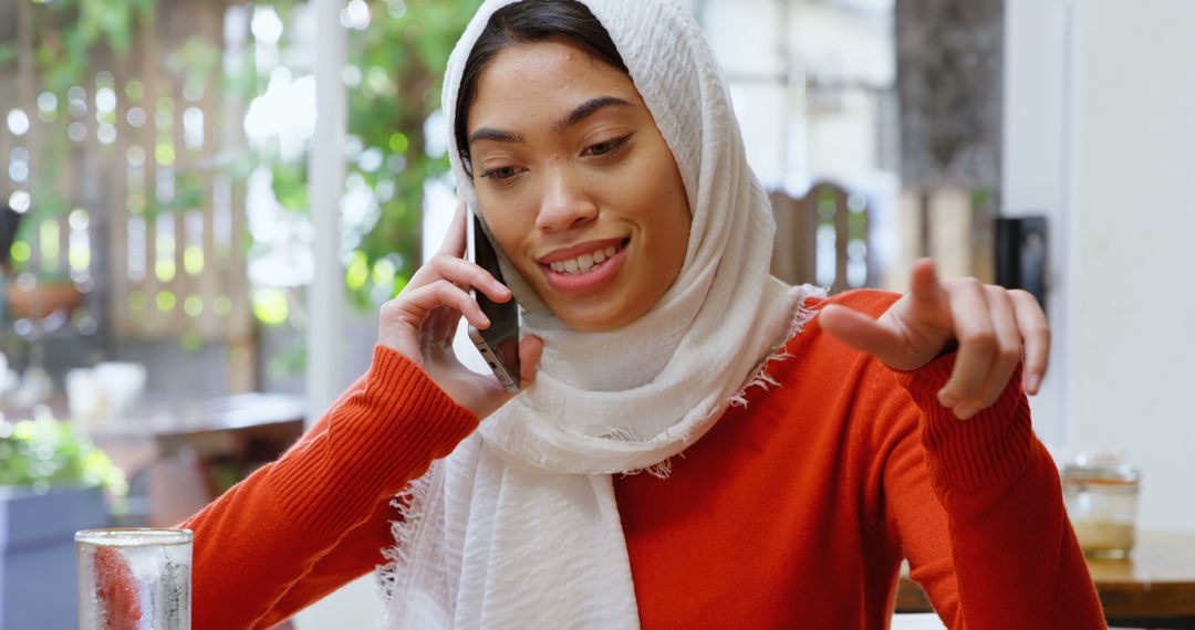 Smiling Woman Wearing Hijab Having Phone Conversation in Cafe - Free Images, Stock Photos and Pictures on Pikwizard.com