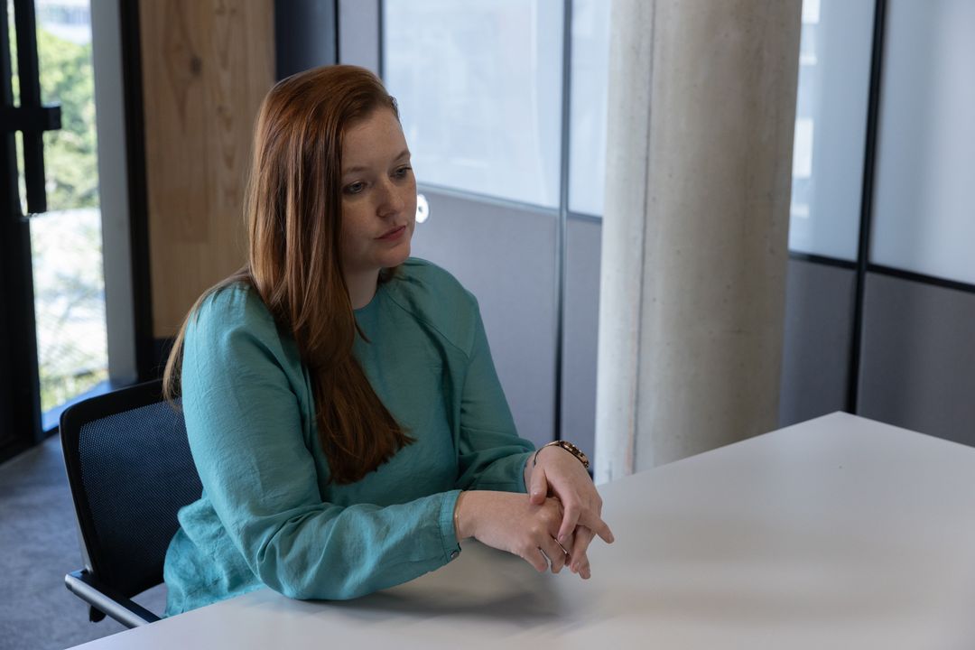 Mid-Adult Woman in Teal Blouse at Conference Table in Office