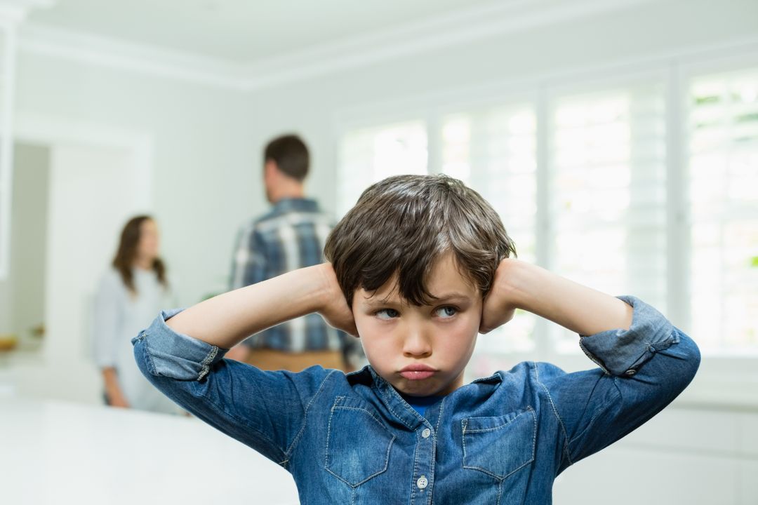 Boy covers his ears with his hands while parents arguing in background - Free Images, Stock Photos and Pictures on Pikwizard.com
