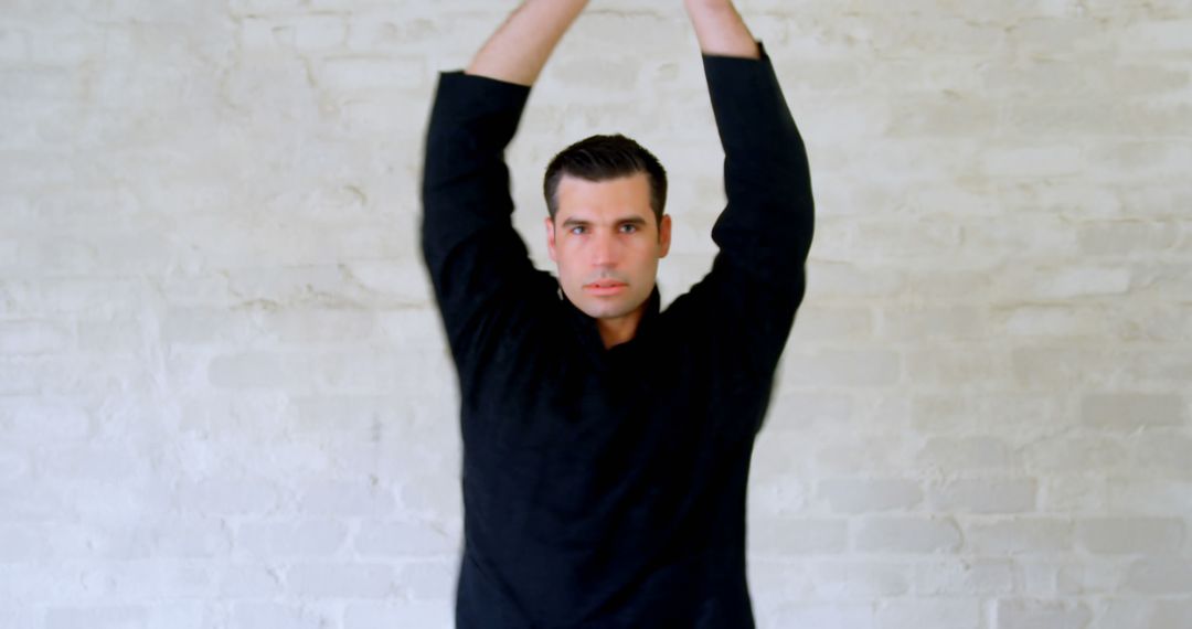 Man in Black Shirt Stretching Against White Brick Wall - Free Images, Stock Photos and Pictures on Pikwizard.com