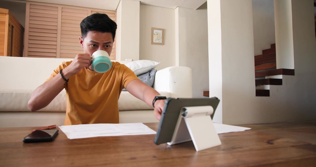 Man Using Tablet while Enjoying Coffee in Modern Living Room