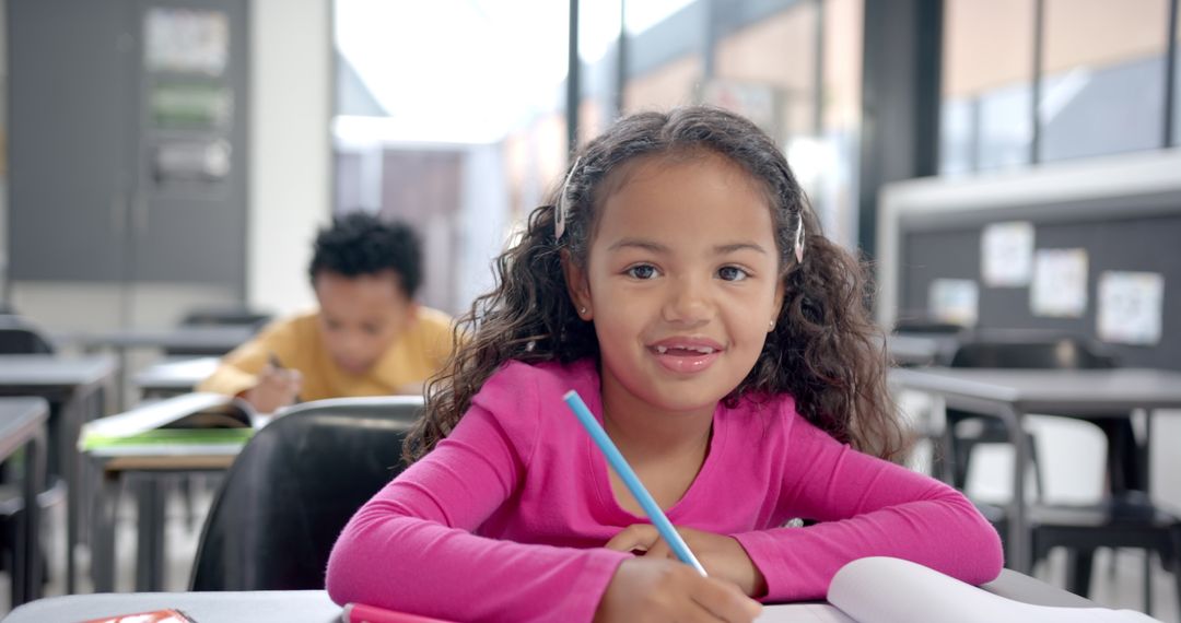 Smiling Girl Writing in Classroom with Boy Studying Behind