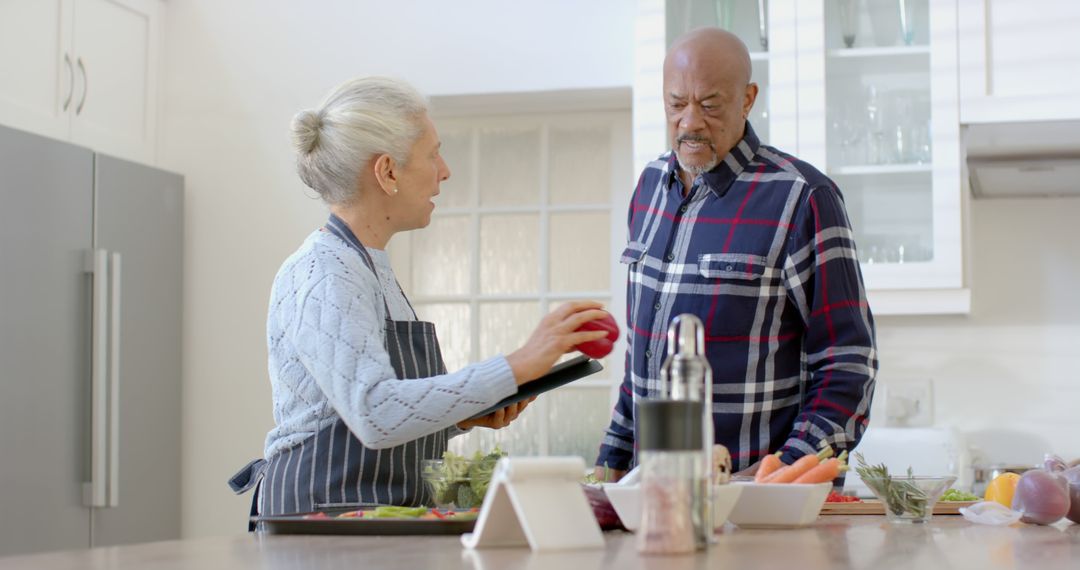 Senior Couple Preparing a Meal Using Tablet in Bright Kitchen