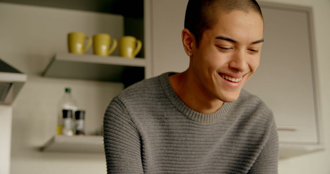 Young Man Smiling in Modern Kitchen with Hanging Mugs - Free Images, Stock Photos and Pictures on Pikwizard.com