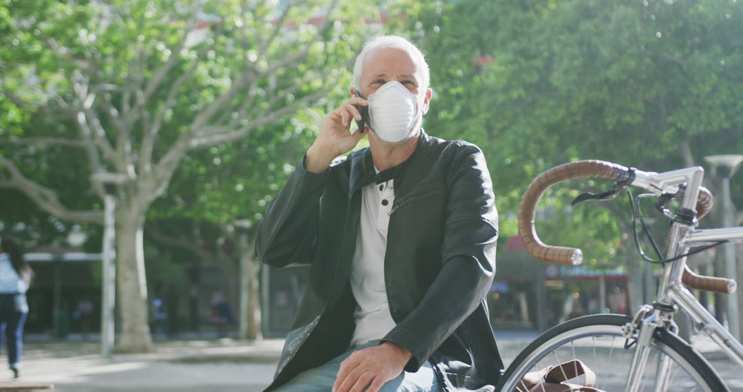 Senior Man in Mask Talking on Phone Outdoors Near Bicycle - Free Images, Stock Photos and Pictures on Pikwizard.com