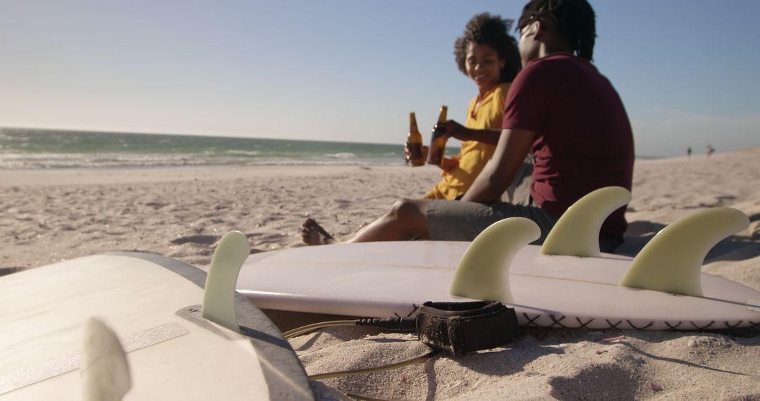 Couple Relaxing on Beach with Surfboards Enjoying Drinks at Sunset - Free Images, Stock Photos and Pictures on Pikwizard.com