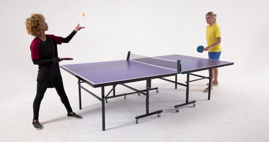 Diverse Female Opponents Playing Table Tennis in Studio Setting