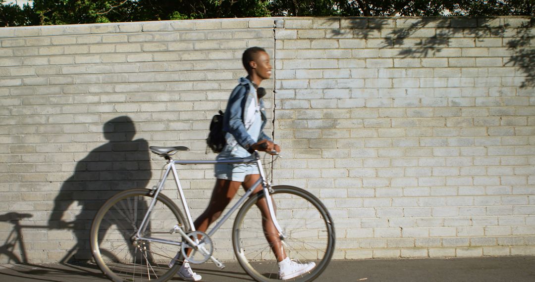 Young Woman Walking Bicycle Along Brick Wall - Free Images, Stock Photos and Pictures on Pikwizard.com