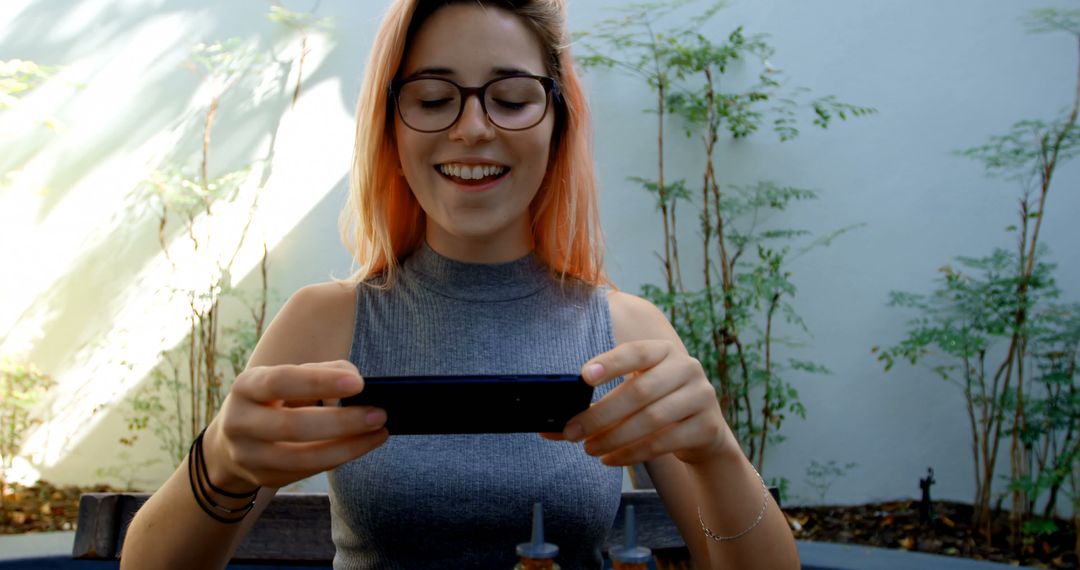 Young Woman Smiling While Using Smartphone Outdoors - Free Images, Stock Photos and Pictures on Pikwizard.com