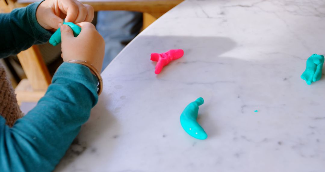 Child Creating with Colorful Playdough on White Table