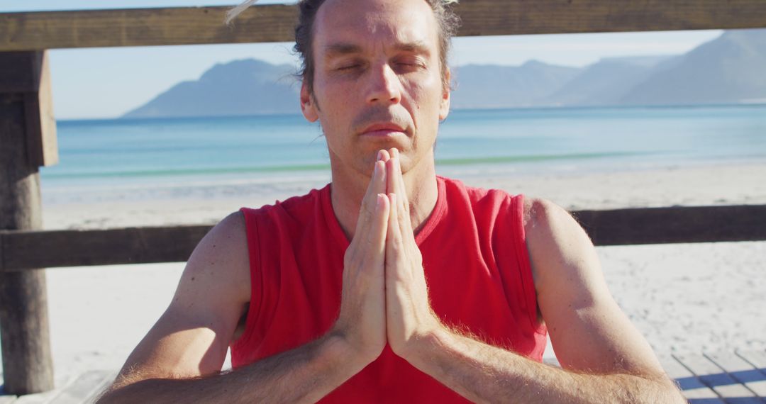 Meditating Man in Red with Hands in Prayer Pose by Beach - Free Images, Stock Photos and Pictures on Pikwizard.com