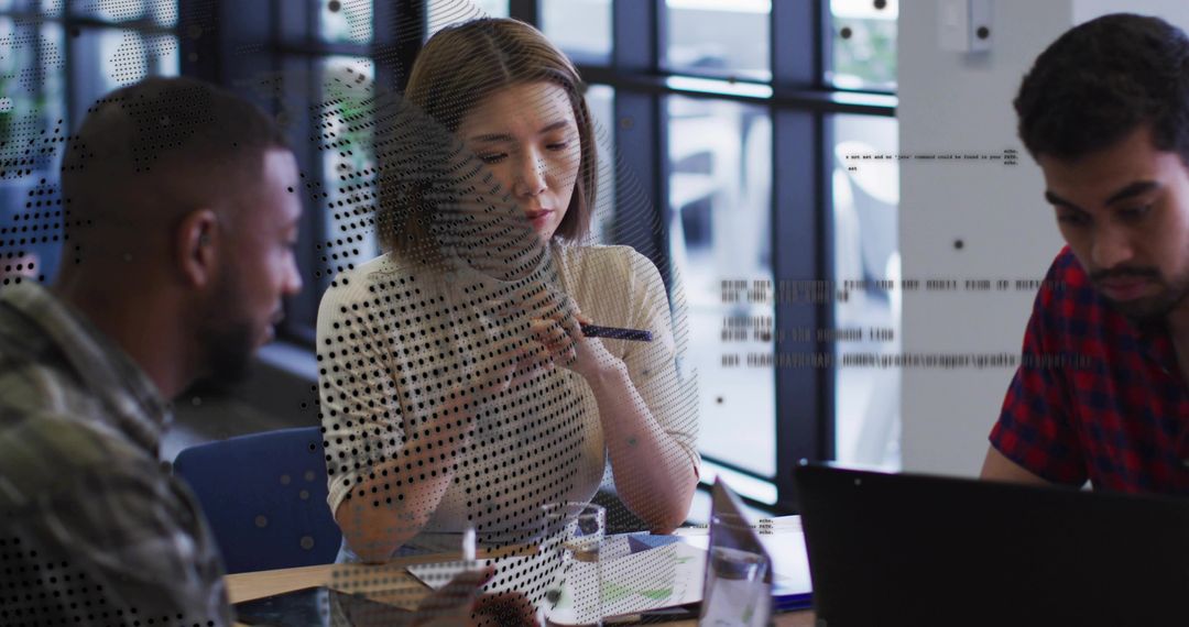 Collaborating team reviewing charts on laptop and tablet in modern glass-walled meeting