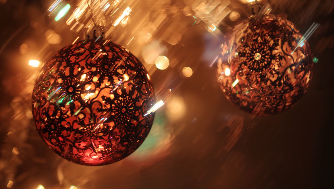 Glowing ornate filigree Christmas bauble casting warm bokeh light and metallic sparkle