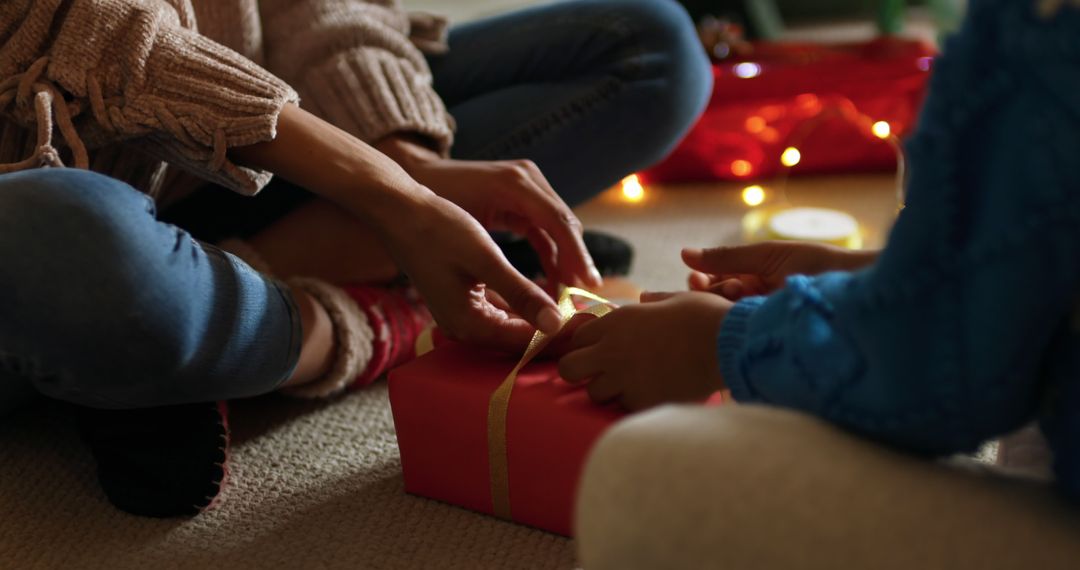 Family Wrapping Christmas Present Together by Candlelight - Free Images, Stock Photos and Pictures on Pikwizard.com