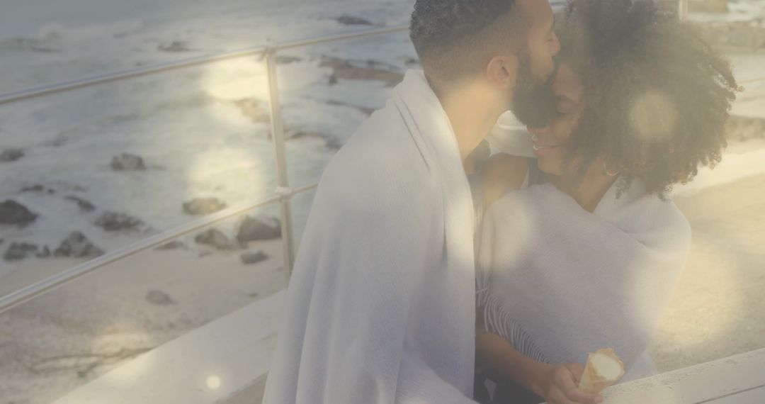 Couple Enjoying Ice Cream Wrapped in Blanket by Sea
