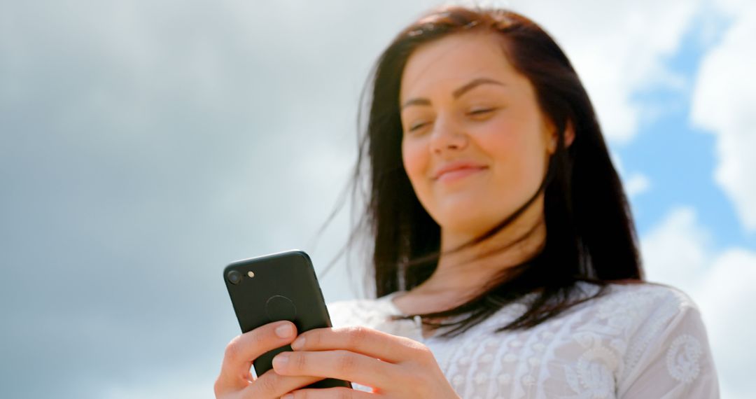 Smiling Young Woman Texting on Smartphone Outdoors - Free Images, Stock Photos and Pictures on Pikwizard.com