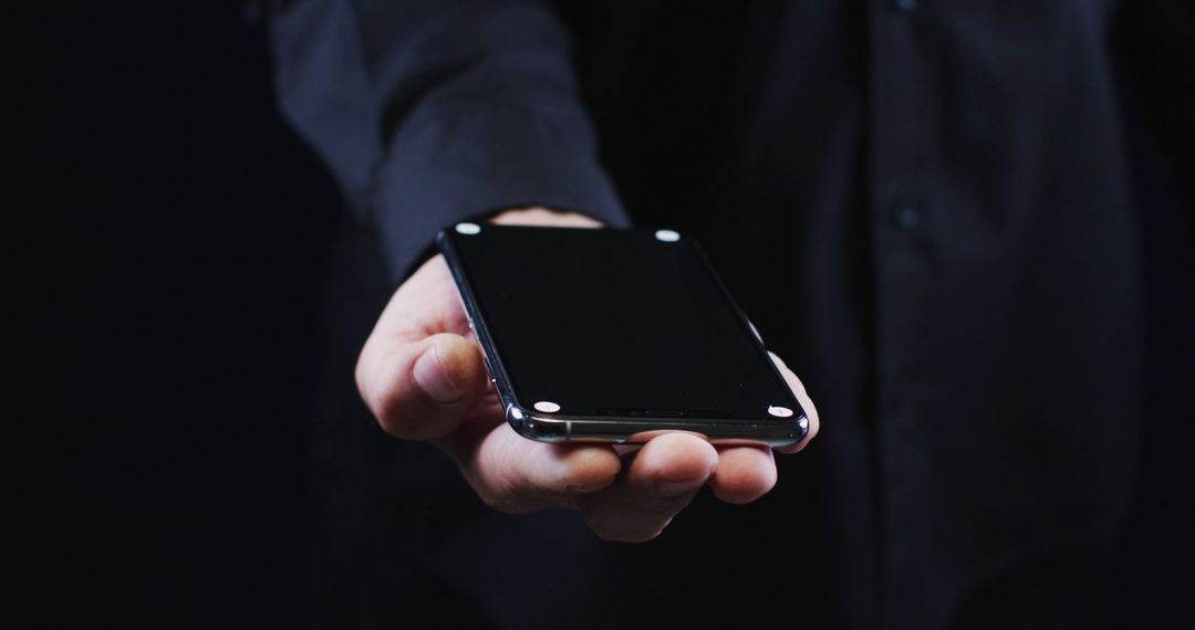 Hand of a caucasian man wearing a black shirt cradling a smartphone - Free Images, Stock Photos and Pictures on Pikwizard.com