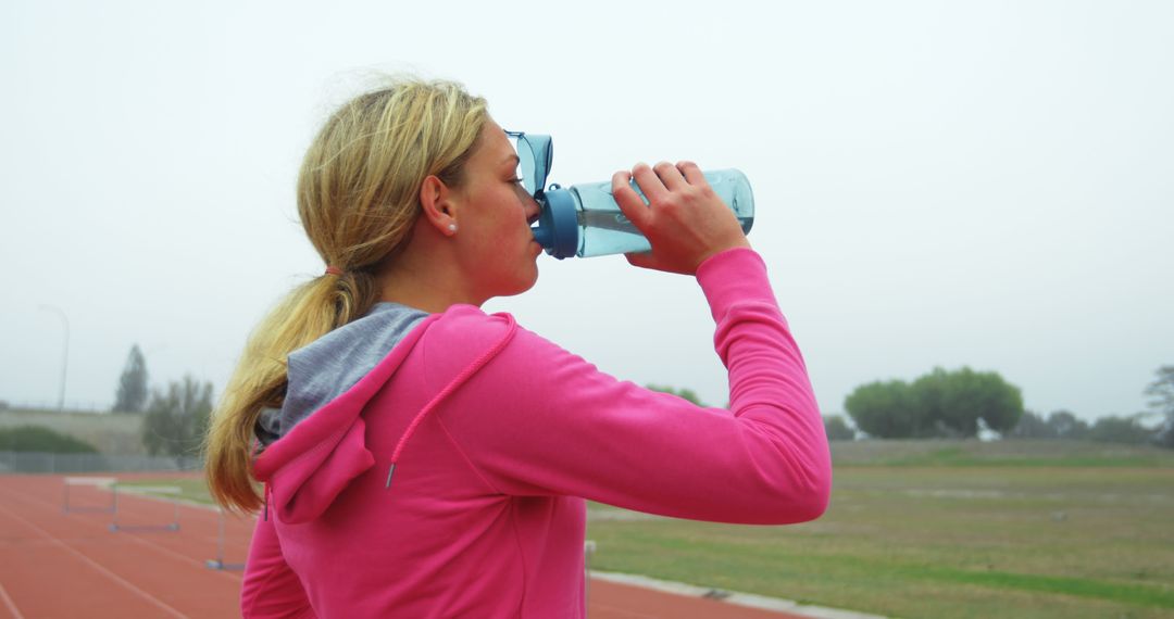 Side view of Caucasian female athlete drinking water on race track - Free Images, Stock Photos and Pictures on Pikwizard.com