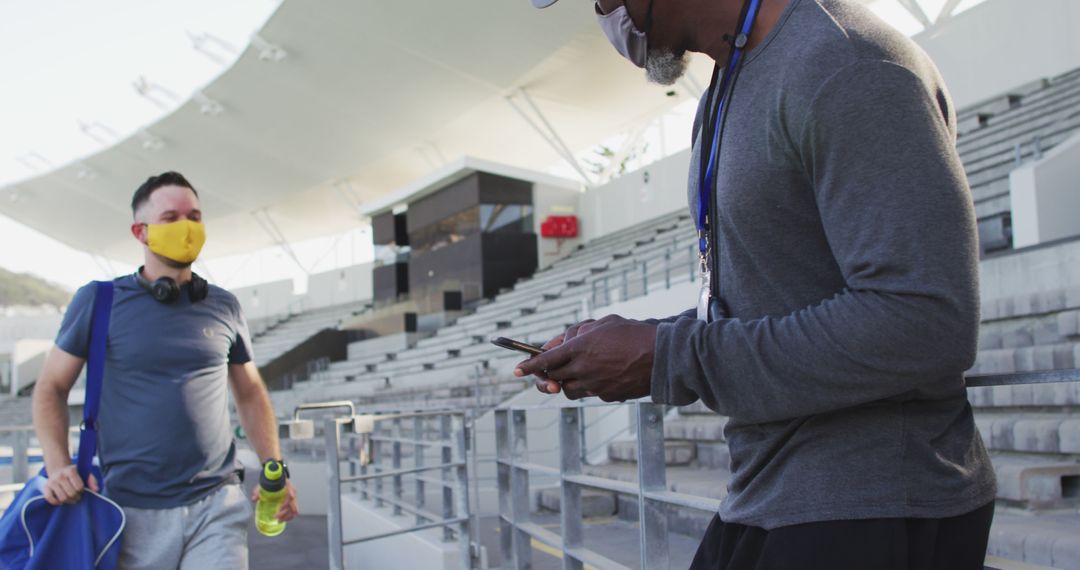 Athletes in Sports Complex with Face Masks Using Smartphone - Free Images, Stock Photos and Pictures on Pikwizard.com