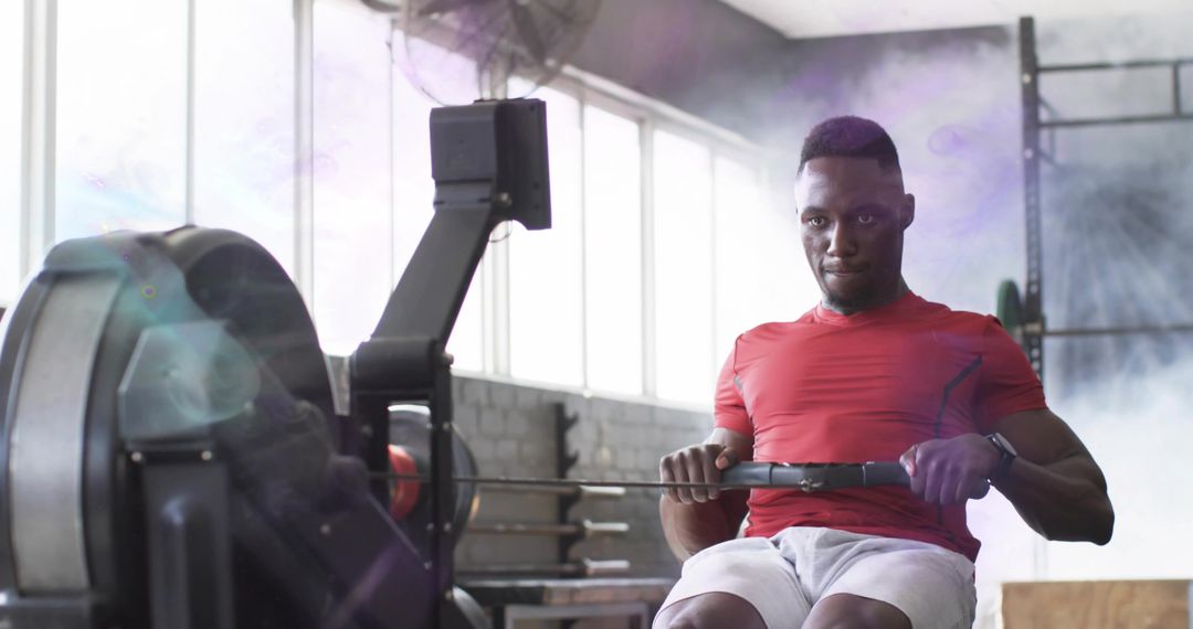 Focused Black Man Exercising on Rowing Machine at Gym