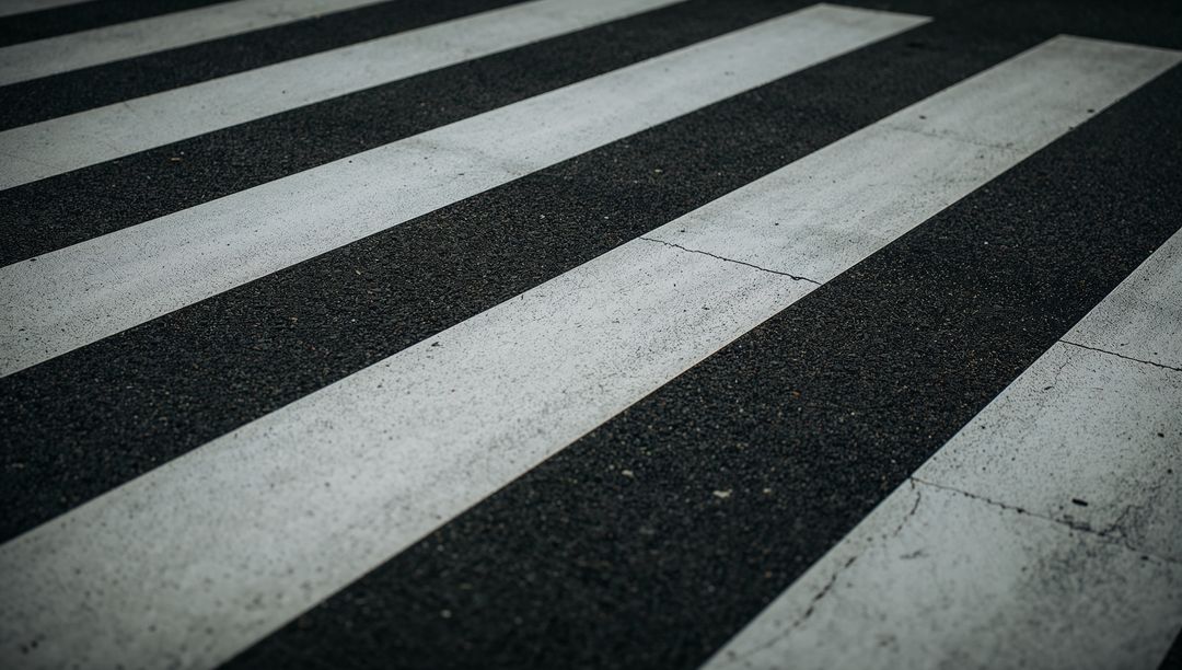 Running diagonal crosswalk stripes on weathered asphalt with cracked paint texture