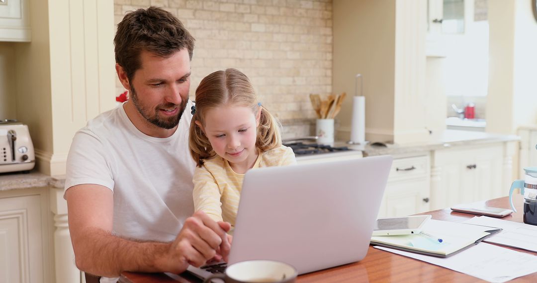 Father and daughter using laptop together in kitchen - Free Images, Stock Photos and Pictures on Pikwizard.com