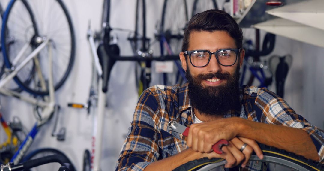 Smiling Bearded Bicycle Mechanic in Workshop with Bikes - Free Images, Stock Photos and Pictures on Pikwizard.com