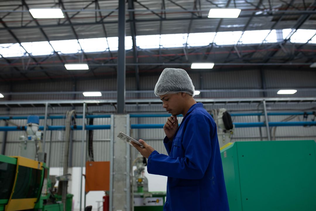 Factory Engineer Using Tablet for Machine Inspection in Industrial Setting