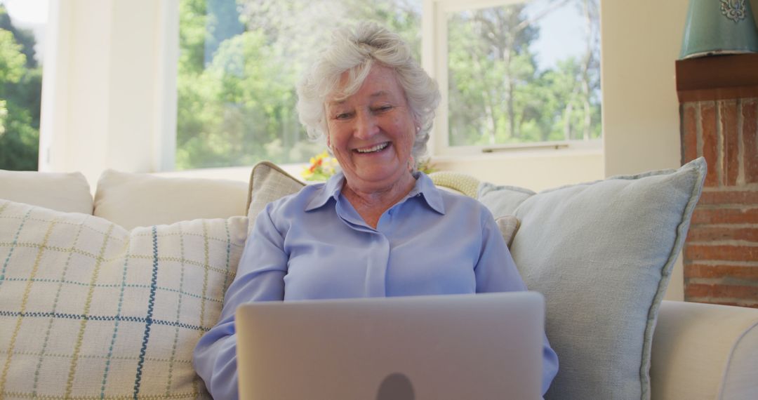 Smiling Elderly Woman Using Laptop on Couch in Cozy Living Room - Free Images, Stock Photos and Pictures on Pikwizard.com