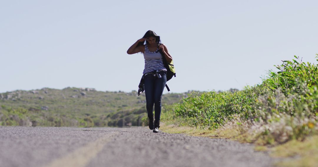 African american woman with backpack walking on a roadside highway - Free Images, Stock Photos and Pictures on Pikwizard.com