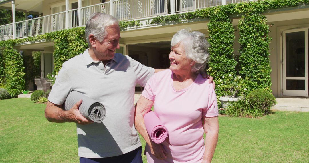 Happy caucasian senior couple exercising embracing walking carrying yoga mats in garden in the sun - Free Images, Stock Photos and Pictures on Pikwizard.com