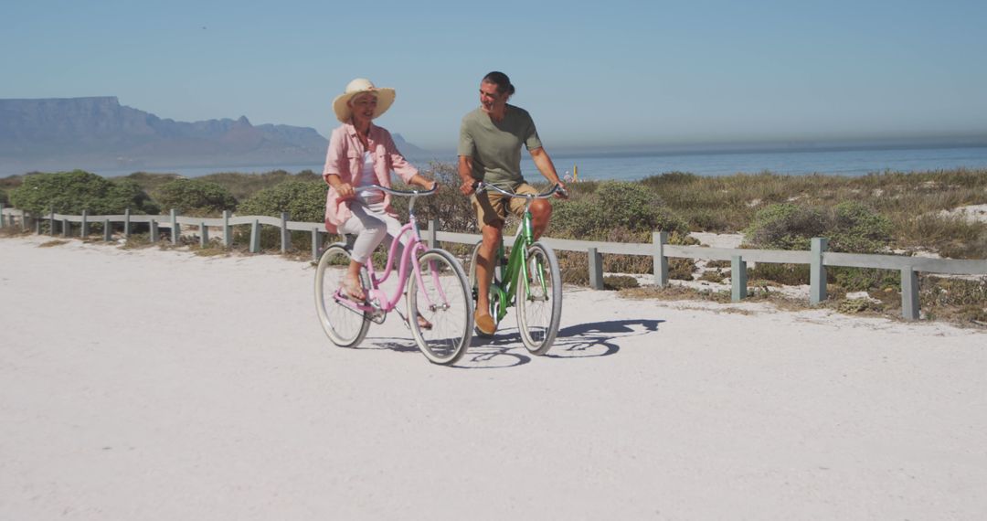 Happy senior caucasian couple riding bikes by seaside - Free Images, Stock Photos and Pictures on Pikwizard.com