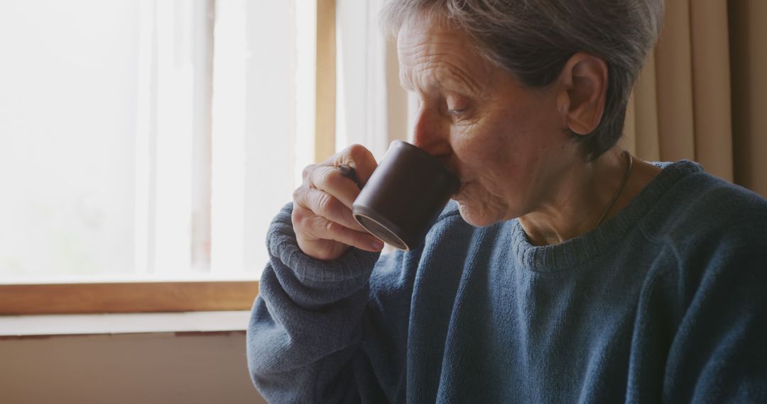 Senior Woman Drinking Coffee at Home Near Window - Free Images, Stock Photos and Pictures on Pikwizard.com