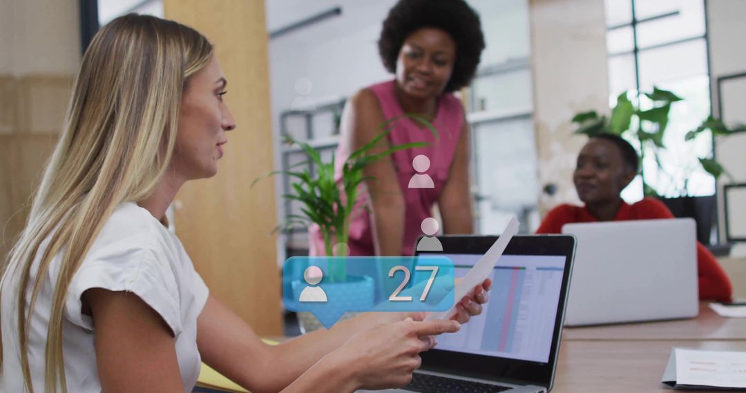Reviewing documents over laptop during collaborative office meeting showing analytics alert