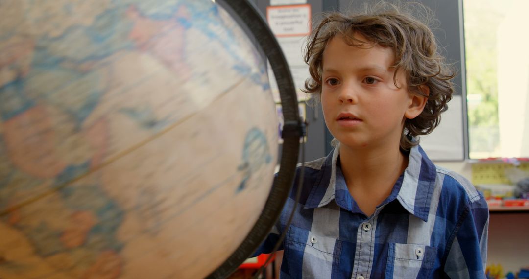 Inquisitive Schoolboy Examining Rotating Globe in Classroom Setting