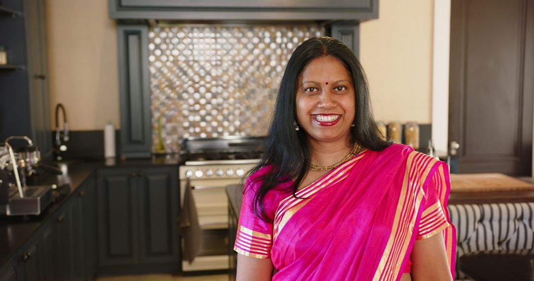 Smiling Indian Woman in Bright Sari Standing in Modern Kitchen
