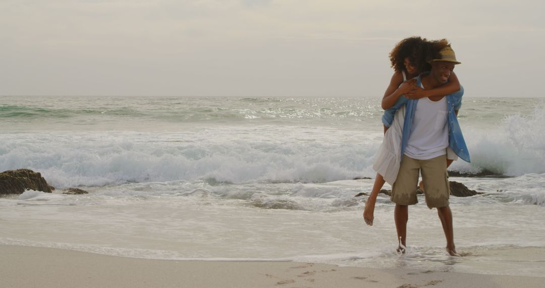 Joyful Couple Piggybacking at Sandy Beach with Waves in Background