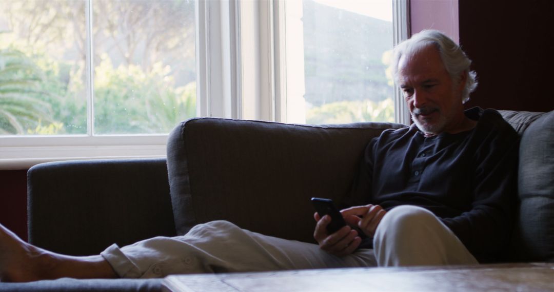 Senior Man Relaxing on Couch Using Smartphone at Home - Free Images, Stock Photos and Pictures on Pikwizard.com