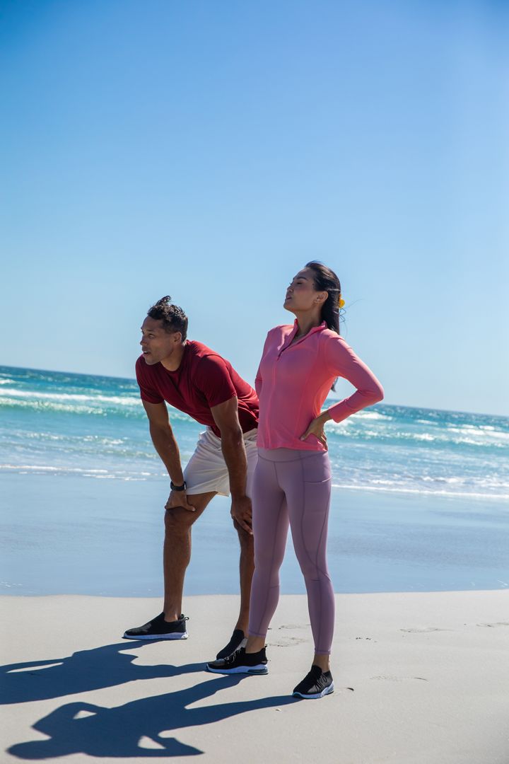 Fit Couple Relaxing After Beachside Run on a Sunny Day