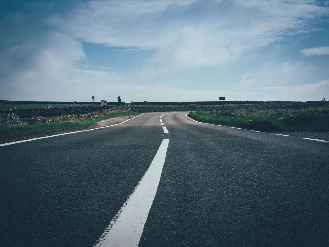 Plain open country road leading to horizon under clear sky