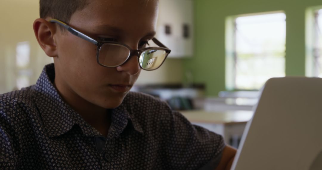 Focused Young Boy Wearing Glasses Using Laptop in Classroom - Free Images, Stock Photos and Pictures on Pikwizard.com