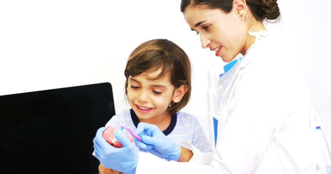 Female Dentist Teaching Child Proper Dental Hygiene with Tooth Model - Free Images, Stock Photos and Pictures on Pikwizard.com