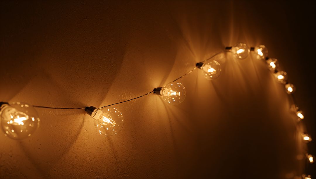 Glowing globe string lights casting warm halos on textured wall showing filaments and bokeh