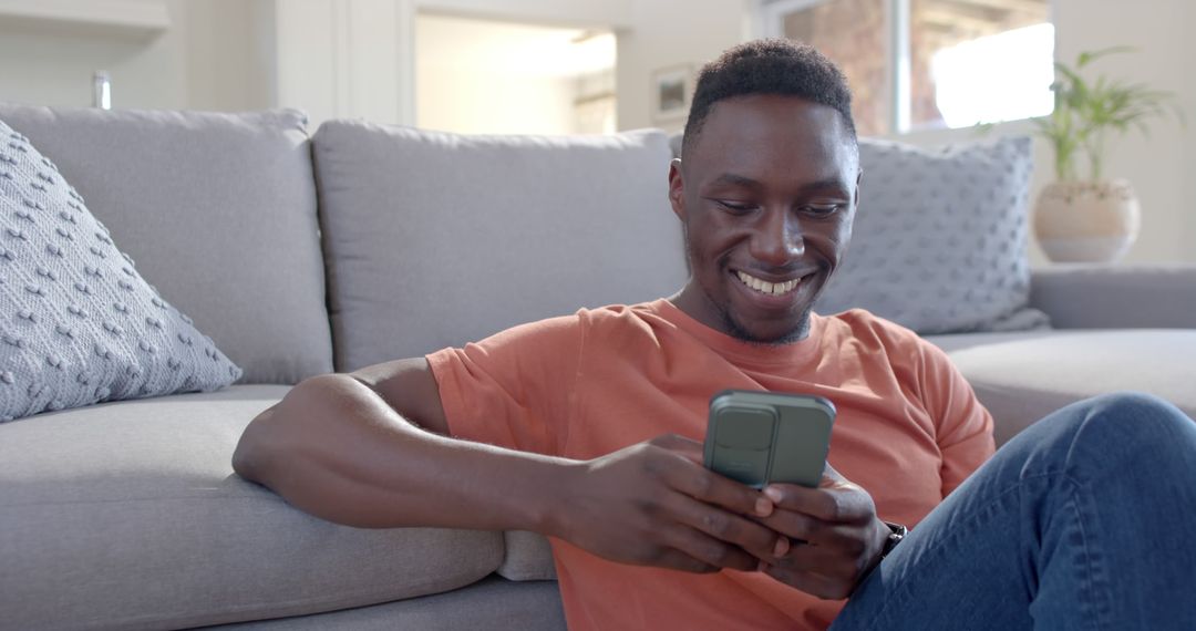 Smiling Young Man Sitting on Floor Using Smartphone at Home - Free Images, Stock Photos and Pictures on Pikwizard.com