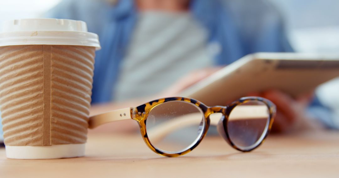 Reading Glasses and Coffee Cup on Desk with Person Using Tablet - Free Images, Stock Photos and Pictures on Pikwizard.com