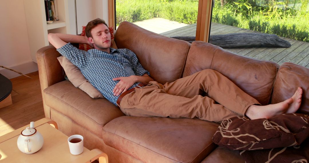 Young Man Relaxing on Couch with Cup of Tea in Living Room - Free Images, Stock Photos and Pictures on Pikwizard.com