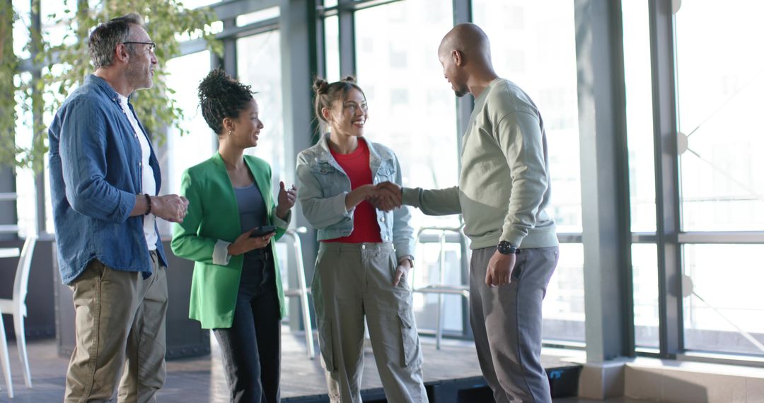 Diverse coworkers shaking hands and networking in bright modern office